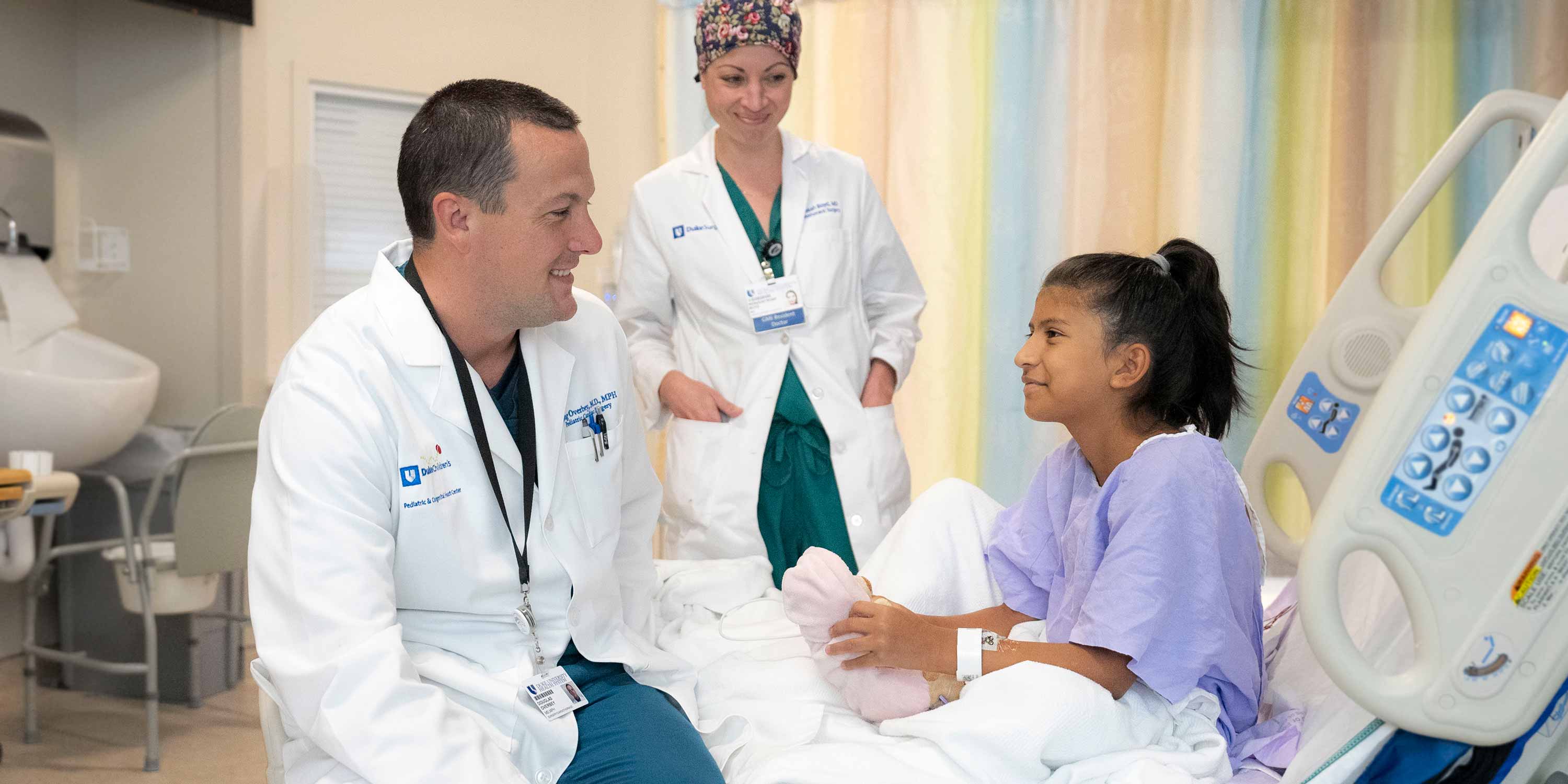 Giselle Olivas talks with Dr. Douglas Overbey and a resident as she recovers from heart surgery.