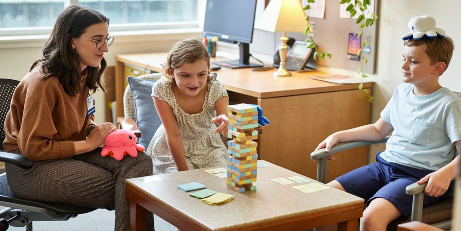 Medical Family Therapist Elizabeth Bautista, LMFT, plays Jenga with the McFadden children.