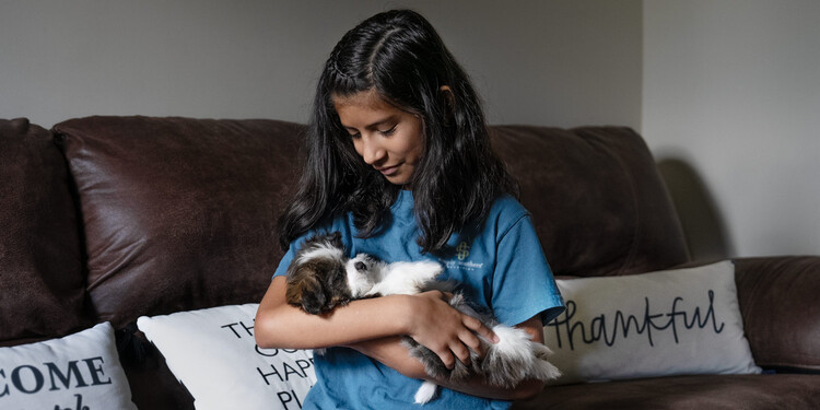 Giselle sits on a couch holding her new puppy