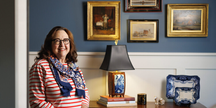 Janet Davas poses for a photo in front of a wall of antique photos and collectibles