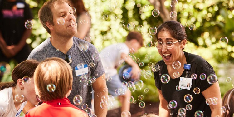 Child Life specialist Micah Sedillos spends time with Graham Alexander and his children as they enjoy bubbles and snow cones at a quarterly in-person meet-up of KidsCAN!