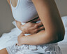 A woman wraps her arms around her abdomen