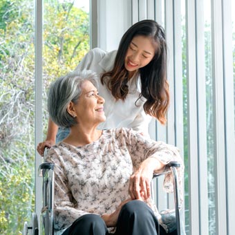 A volunteer pushes an elderly woman in a wheelchair