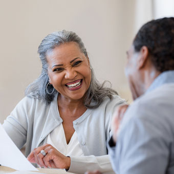 An elderly man and woman look over a piece of paper as they chat together.